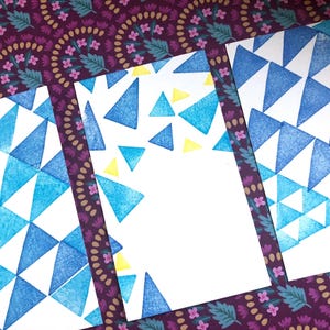 Puede incluir: Tres tarjetas blancas con patrones de triángulos azules y amarillos impresos en ellas. Las tarjetas están dispuestas en una fila, con la tarjeta superior superponiéndose ligeramente a la tarjeta del medio y la tarjeta del medio superponiéndose ligeramente a la tarjeta inferior.