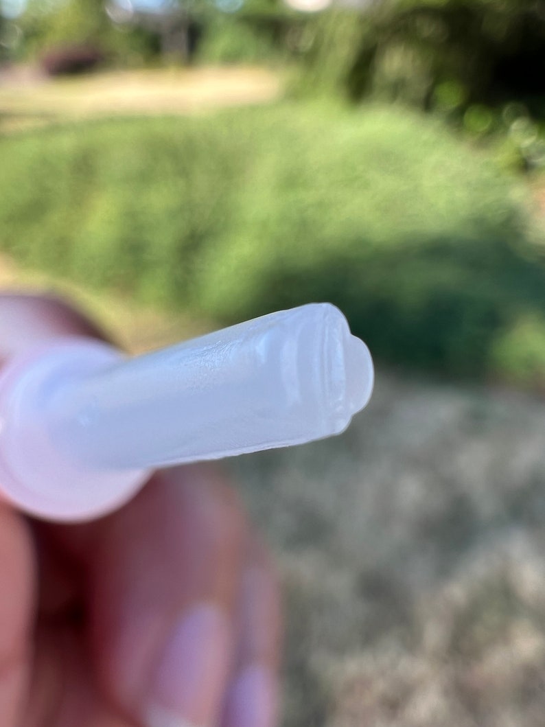 May include: Close-up of a clear plastic applicator tip with a small opening at the end.