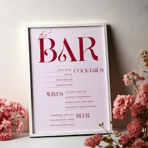 Könnte beinhalten: Ein gerahmter Druck mit dem Wort „BAR“ in großen burgunderfarbenen Buchstaben. Darunter listet der Druck Cocktails, Weine und Biere auf, darunter Spicy Marg, Mojito und Ironwood Pale Ale. Rosa Blumen sind im Vordergrund.