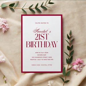 May include: A formal invitation with a burgundy border and text. The invitation reads "Annabel's 21st Birthday" in a stylish font. Additional details include the date, time, location, RSVP information, and dress code. The invitation is surrounded by floral and greenery accents.