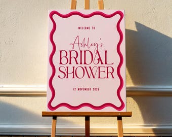 Könnte beinhalten: Ein rosafarbenes und rotes Schild für eine Brautparty mit einem gewellten Rand. Das Schild lautet "Willkommen zu Ashley's Bridal Shower" und "12. November 2026".