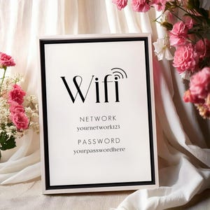 Könnte beinhalten: Ein weißer, gerahmter Schild mit schwarzem Text, der "Wifi" mit einem Wifi-Symbol lautet. Das Schild enthält auch den Text "Netzwerk" und "yournetwork123" sowie "Passwort" und "yourpasswordhere".
