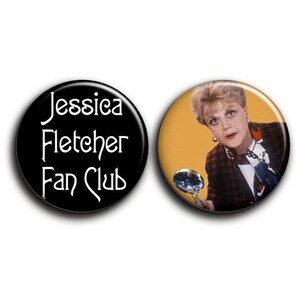 Op de afbeelding: Twee ronde buttons. Eén zwarte button met de witte tekst "Jessica Fletcher Fan Club". De andere button toont een kleurenfoto van een vrouw met een vergrootglas.