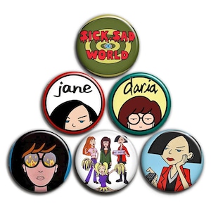 May include: A selection of seven circular badges with cartoon characters and text. The badges show images of a woman with glasses, a woman with black hair, and a group of women. One badge reads "Sick Sad World."
