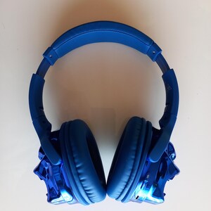 May include: Blue wireless headphones with a metallic blue finish on the earcups. The headphones have a padded headband and earcups.