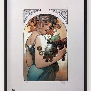May include: A framed print of a woman in a blue dress holding a basket of fruit. The woman has long, flowing hair and is wearing a gold necklace. The print is in a black frame and has a white background.