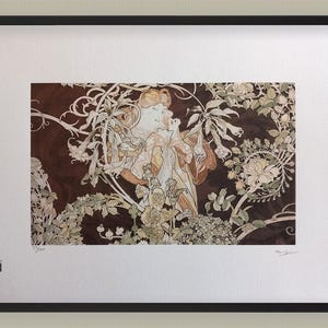May include: Art print in a black frame, depicting a woman amidst floral designs in brown, beige, and green hues. The artwork is in the Art Nouveau style, with elegant lines and decorative details. The print is set in a white mount.
