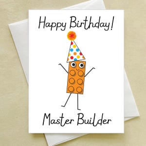 May include: A birthday card featuring a cartoon Lego brick wearing a party hat and the text "Happy Birthday! Master Builder".