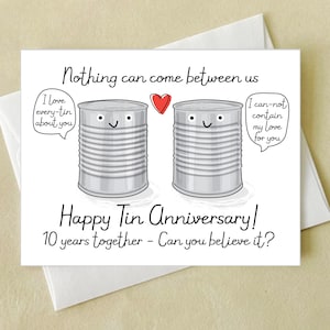 May include: A white greeting card with the text "Nothing can come between us" and "Happy Tin Anniversary!" features two cartoon tin cans with smiling faces and a red heart. The card celebrates 10 years together.