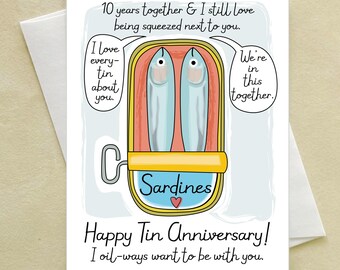 May include: A greeting card featuring a cartoon illustration of two sardines in a tin. Text reads: 10 years together & I still love being squeezed next to you. I love every-tin about you. We're in this together. Happy Tin Anniversary! I oil-ways want to be with you.