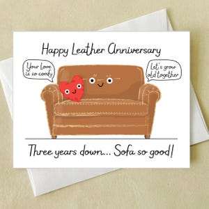 May include: A greeting card with a brown cartoon sofa and a red heart. The text reads "Happy Leather Anniversary" and "Three years down... Sofa so good!" with speech bubbles saying "Your love is so comfy" and "Let's grow old together."