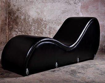 May include: A black leather chaise lounge with a curved design. The lounge has a smooth, sleek surface and is supported by a metal frame.