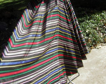May include: A black and white striped skirt with red, green, blue, and yellow stripes. The skirt is full and flowing, and it is made of a shiny fabric.
