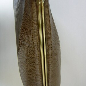 May include: A brown leather clutch purse with a gold metal clasp. The purse has a textured, snake-like pattern.