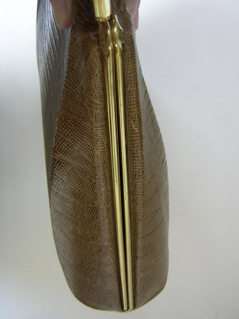 May include: A brown leather clutch purse with a gold metal clasp. The purse has a textured, snake-like pattern.