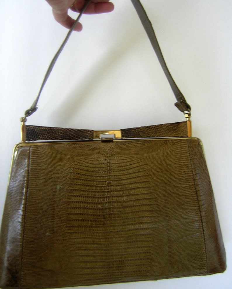May include: A brown leather handbag with a gold clasp and a long strap. The bag has a textured, snakeskin-like pattern.
