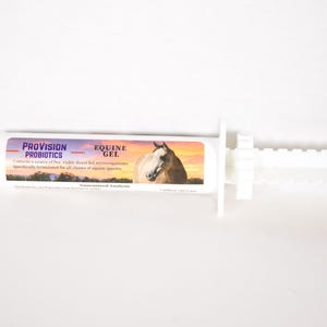 Peut inclure: Une seringue en plastique blanche avec une étiquette indiquant "PROVISION PROBIOTICS EQUINE GEL". L'étiquette présente également une image de la tête d'un cheval sur fond de coucher de soleil.