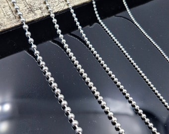 May include: Five silver ball chain necklaces of varying lengths, displayed on a wooden surface.