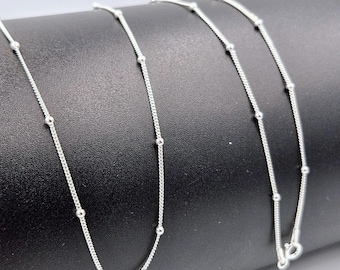 May include: A silver chain necklace with small round beads. The chain is delicate and has a simple design.