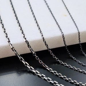May include: Five silver chains of varying lengths and thicknesses, displayed on a white surface.