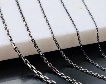 May include: Five silver chains of varying lengths and thicknesses, displayed on a white surface.