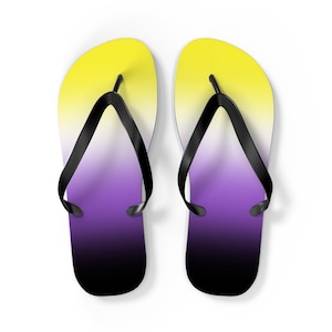 May include: A pair of black flip-flops with a yellow to purple ombre design. The flip-flops are on a white background.