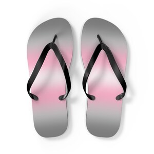 May include: A pair of black flip-flops with a pink and gray ombre design.