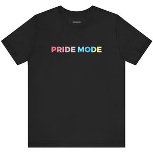 Może przedstawiać: Czarny T-shirt z napisem "PRIDE MODE" w kolorach tęczy.