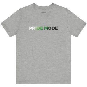 May include: A heather grey t-shirt with the text "PRIDE MODE" in green, white, and black lettering.