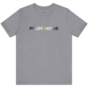 Może przedstawiać: Szary t-shirt z nadrukiem "PRIDE MODE" w kolorze gradientowym: szary, zielony i biały.