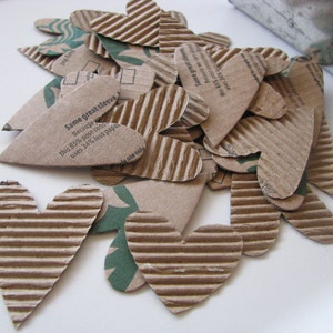 May include: A pile of brown cardboard hearts with a white background. The hearts have a corrugated texture and some have text printed on them that reads "Same great sleeve Because this 85% post-con uses 34% less pape le use only".