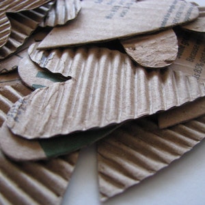 May include: A pile of brown cardboard hearts with a green and white label that reads "Because 45.8% post-consumer uses 34% less..."
