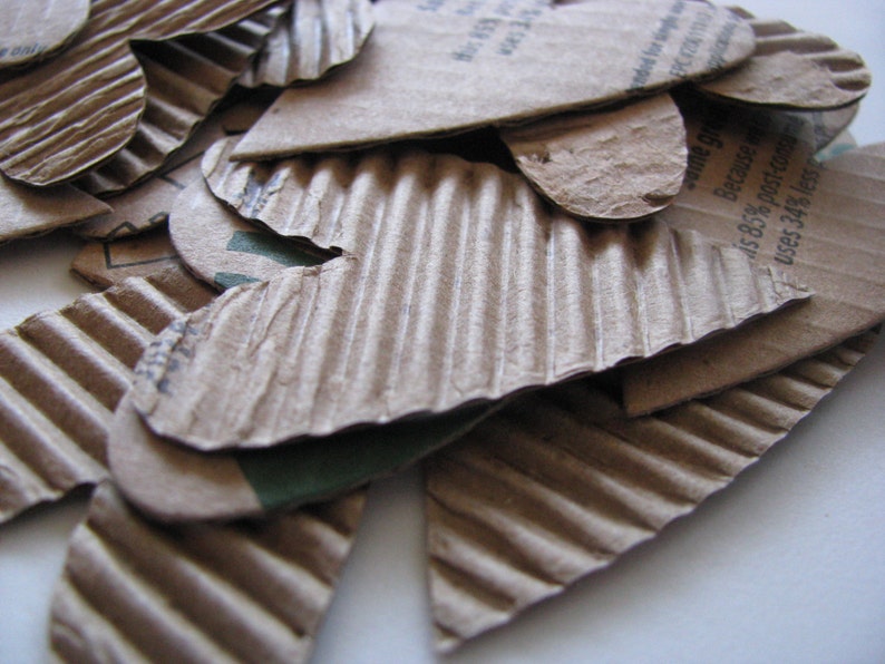 May include: A pile of brown cardboard hearts with a green and white label that reads "Because 45.8% post-consumer uses 34% less..."