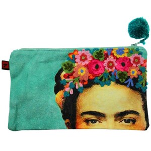 Può includere: Una pochette con cerniera in tela turchese con un ricamo floreale colorato e un'immagine stampata del viso di Frida Kahlo. La pochette ha un tiretto con pompon turchese.