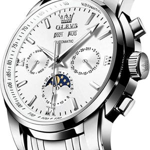 May include: A silver-toned automatic wristwatch with a white dial, featuring a crown logo, the text OLEVS, 2021, and AUG. The watch includes three sub-dials for day, date, and a moon phase display, with silver hour markers and hands on a metallic band.