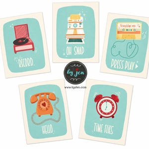 May include: A set of five rectangular art prints on a light background, each featuring a teal border and a retro object: a red record player with 'FOR THE RECORD', a camera with 'OH SNAP', a cassette with 'PRESS PLAY', an orange phone with 'HELLO', and a red alarm clock with 'TIME FLIES'.