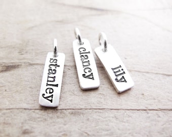 May include: Three silver charm tags with the names "Stanley", "Clancy", and "Lily" engraved on them.