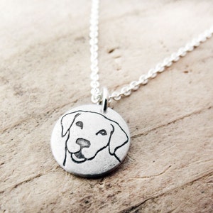 May include: A silver necklace with a round pendant featuring a line drawing of a Labrador Retriever's head.