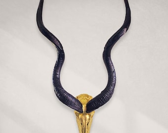 May include: A decorative wall hanging featuring a skull with large, curved horns. The horns are dark blue, and the skull is gold. The piece is designed to be mounted on a wall and adds a unique touch to any space.