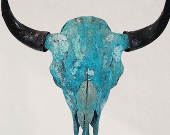 May include: A decorative cow skull with a turquoise patina finish. The skull has black horns and a weathered appearance, creating a rustic aesthetic. This piece is suitable for wall decor.