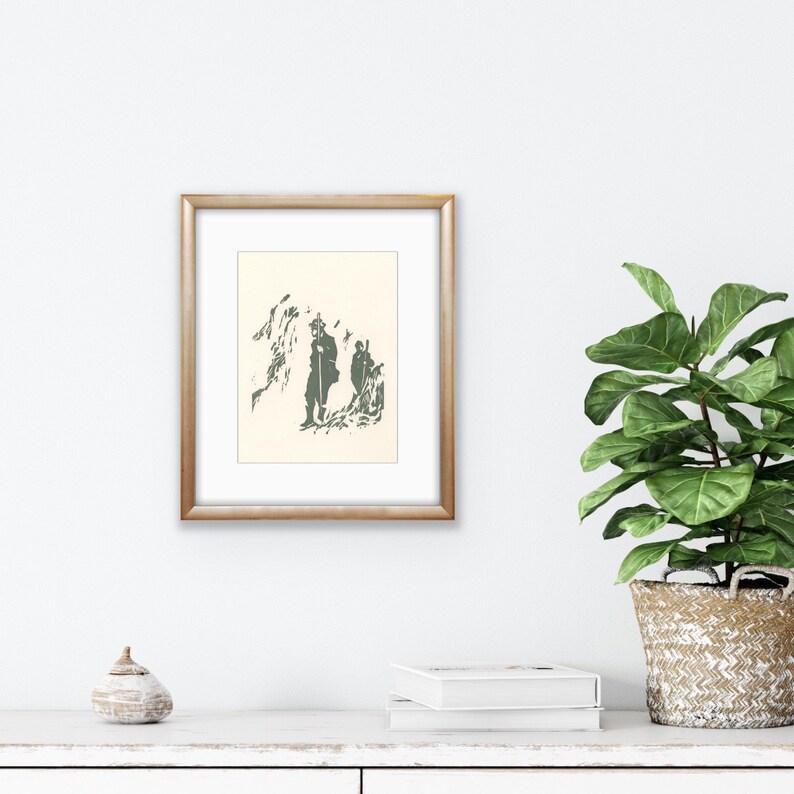 May include: A framed print of a black and white illustration of two figures walking in a mountainous landscape. The figures are silhouetted against a white background.