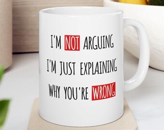 Może przedstawiać: Biały ceramiczny kubek do kawy z czarnym tekstem, który brzmi "I'm NOT arguing I'm just explaining why you're WRONG". Słowa "NOT", "arguing", "explaining" i "WRONG" są czerwone.