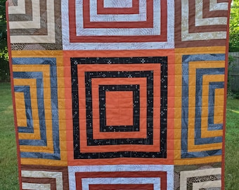 Graphic baby / toddler / lap quilt in warm earth colors of rust, gold, terracotta, tan beige and black, all cotton, machine washable.