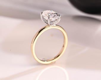 May include: A gold engagement ring with a large oval-shaped diamond set in a pave setting. The band is thin and has a polished finish.