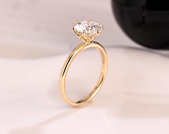 May include: A gold solitaire engagement ring with a large, clear oval-shaped diamond.