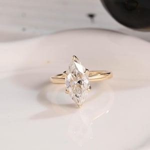 May include: A gold engagement ring with a large pear-shaped diamond.