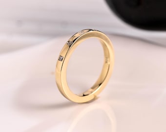 Puede incluir: Un anillo de banda de oro simple con tres pequeños diamantes engastados en la banda.