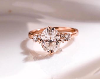 May include: A rose gold engagement ring with a large oval-shaped center diamond and smaller diamonds on the band.