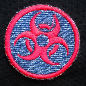 May include: A round, blue denim patch with a red biohazard symbol embroidered on it.