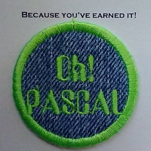 May include: A green and blue circular patch with the text "Oh! Pascal" embroidered in green on a blue denim background.